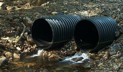 Photo of the outlet of twin culverts perched above the streambed.  Improper culvert installation blocks and prevents upstream passage for the wild brook trout population.
